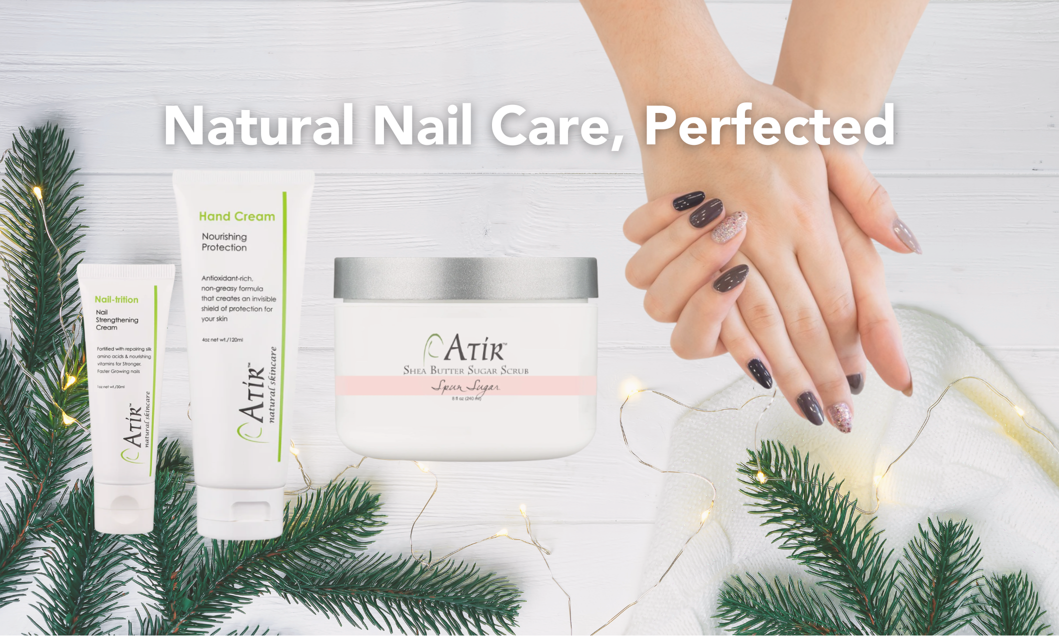 ATiR Natural Nail Care Perfected with woman's manicured hands next to ATiR Nail-trition, Hand Cream, and Shea Butter Sugar Scrub with holiday background