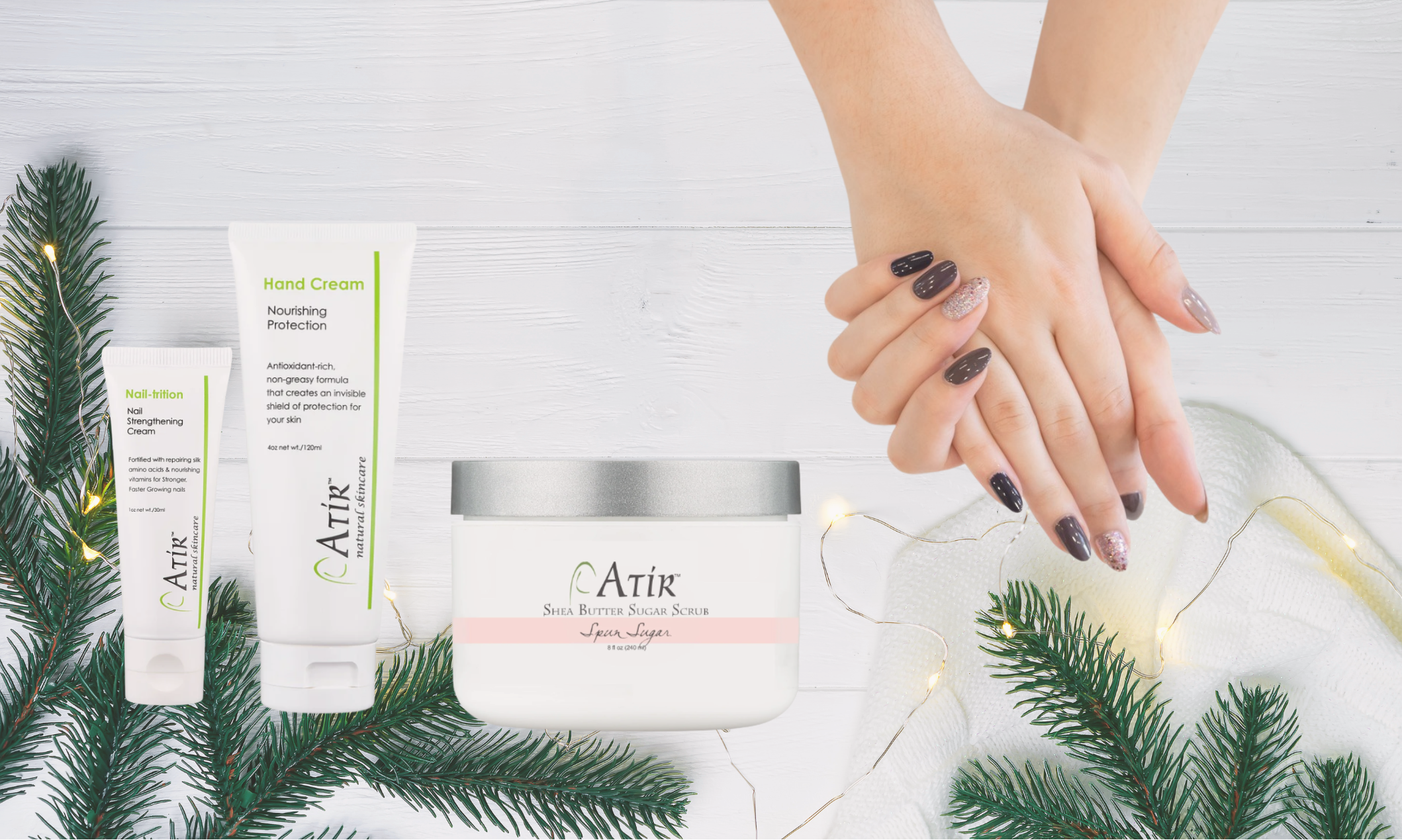 Woman's manicured hands with ATiR Natural Nail Care products including Nail-trition, Hand Cream, and Shea Butter Sugar Scrub over holiday background